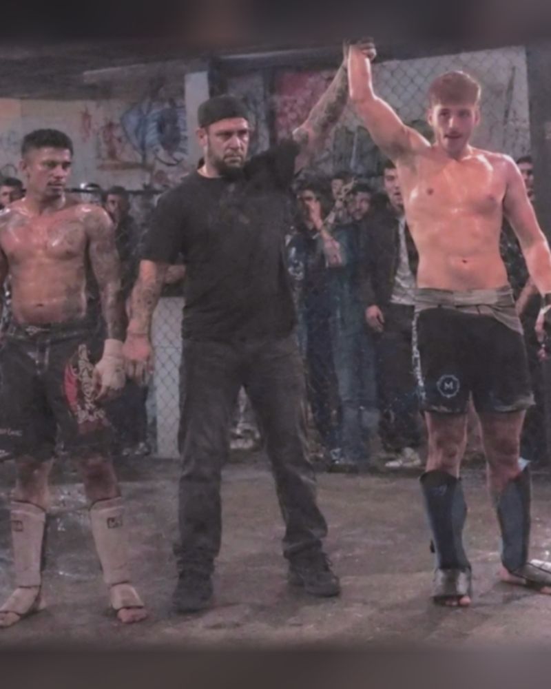 Miliadis Nikos with his hand raised beside the referee and his opponent